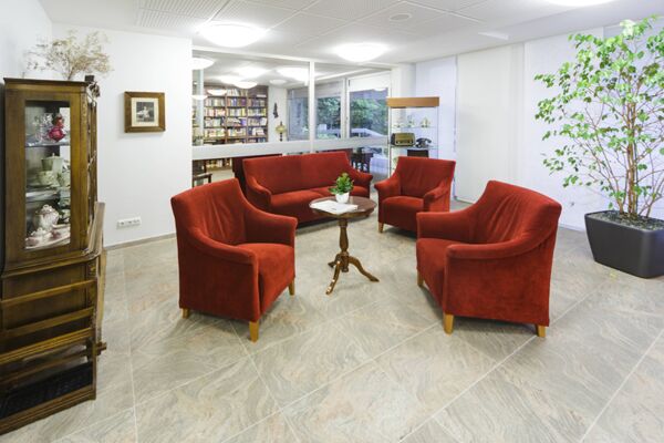 Aufenthaltsbereich im Altenheim Rheindahlen mit Sofa und Sesseln in einem rot Ton